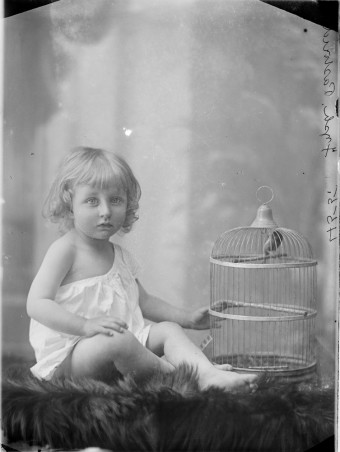 Small child with caged bird, sitting on rug with legs crossed, whole-length, full face, ca. 1880-ca. 1900. (www.slv.vic.gov.au)