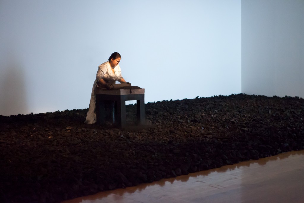 Melati Suryodarmo performs I'm a ghost in my own house 2012, a 12 hour durational work in which she crushes hundreds of kilograms of charcoal as a transformative and symbolic act of life's energy. / Image courtesy of QAGOMA