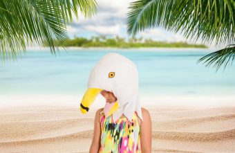 person wearing a fabric bird head costume in a tropical background.