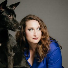 Black dog and woman in blue shirt looking to one side. Image for the production 'Bitch' as part of Brisbane Festival 2017