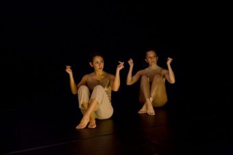 Melanie Lane and Lillian Steiner in beige costumes sitting on stage