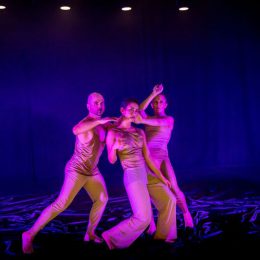 three dancers in pink light on stage