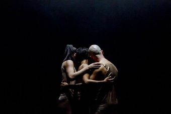 three people on a dark stage facing away from the camera. Night Dance production. Credit: Arts House