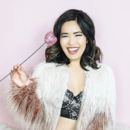 Diana Nguyen holding a rose dressed in exposed lingerie and a fur bolero